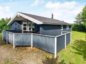 a blue house with a large deck in a yard at 7 person holiday home in Hemmet in Falen