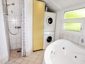 a bathroom with a tub and a washing machine at 7 person holiday home in Hemmet in Falen