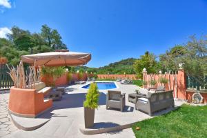 a patio with chairs and an umbrella and a pool at Villa Alex in Sinarádes