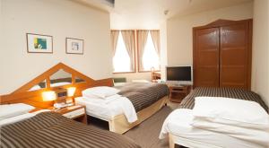 a hotel room with two beds and a television at Hotel Clio Court Hakata in Fukuoka