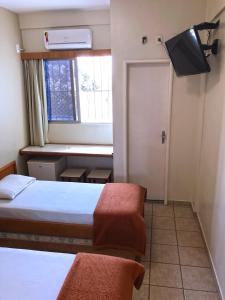 Habitación pequeña con 2 camas y ventana en Hotel Serra das Águas, en Goiânia