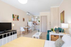 ein Wohnzimmer mit einem Sofa und einem TV sowie eine Küche in der Unterkunft Anelia Studio Lefkada in Lefkada Town