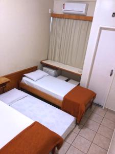 a bed room with two beds and a desk at Hotel Serra das Águas in Goiânia