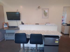 a kitchen with two chairs and a counter with a television at Alpine View Motel in Te Anau