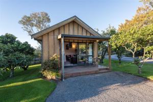 a small house with a porch in a yard at Kerigold Secluded Chalets Motel in Kerikeri