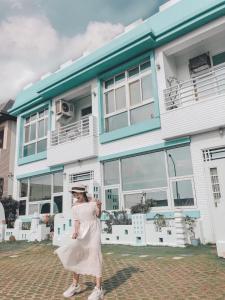 a woman in a white dress standing in front of a house at Happiness Factory in Huxi