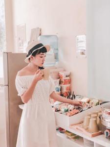 a woman in a white dress standing in front of an open refrigerator at Happiness Factory in Huxi