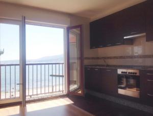 uma cozinha com uma varanda com vista para o oceano em Apartamento Playa de Boiro em Boiro