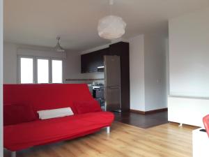 um sofá vermelho numa sala de estar com uma cozinha em Apartamento Playa de Boiro em Boiro