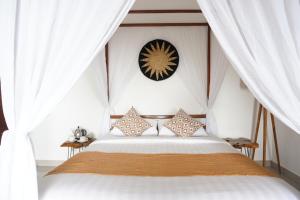 a bedroom with a bed with white curtains and a clock at Aryautama Garden Villa in Munduk