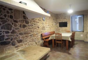 een eetkamer met een tafel en een stenen muur bij Casa do Rei in Boiro