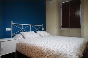 een slaapkamer met een bed met een blauwe muur bij Casa do Rei in Boiro