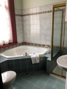 a bathroom with a tub, toilet and sink at Vue Grand Hotel in Queenscliff