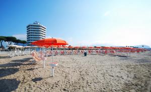 a beach with chairs and umbrellas and a building at Torre Del Sole in Terracina