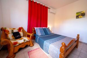 - une chambre avec un lit, une chaise et des rideaux rouges dans l'établissement Viva Nature, à Garnier
