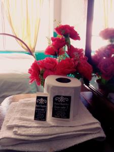 a roll of toilet paper and red flowers on a table at Nápoles Emperador II in Ambato