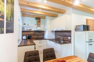 cocina con armarios blancos, mesa y sillas en Apartmaji MM en Bohinj