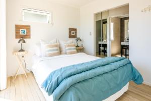 a bedroom with a large white bed with blue sheets at Bach on Burrell in Oneroa