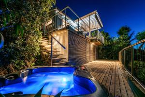 a house with a hot tub on a wooden deck at Bach on Burrell in Oneroa