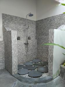 La salle de bains est pourvue d'une douche et d'un mur en briques. dans l'établissement Sunmoonstarvillas Yogyakarta, à Jarakan