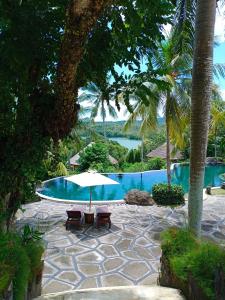 a swimming pool with two chairs and an umbrella at Taman Wana Resort Palasari in Negara