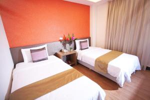 - 2 lits dans une chambre d'hôtel aux murs orange dans l'établissement Jinbao Hotel, à Kaohsiung