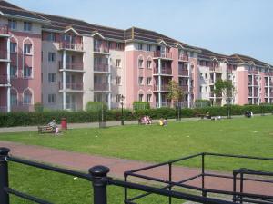 un grand bâtiment rose avec des personnes assises dans un parc dans l'établissement Glen House Room Only Accommodation, à Youghal