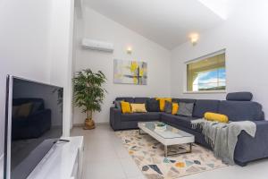 a living room with a blue couch and a tv at VILLA SKURA private heated pool 32m2, summer kitchen, 4 bedrooms, garden in Duće