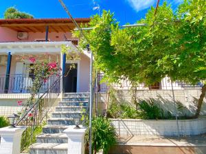 a house with stairs and trees in front of it at Nissaki Apartments and Vasilis House in Nisakion