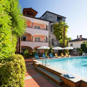 um hotel com uma piscina com cadeiras e guarda-sóis em Romantik Hotel Castello Seeschloss em Ascona