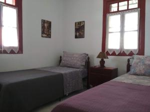 a bedroom with two beds and two windows at Maison des amis in Vatopedi