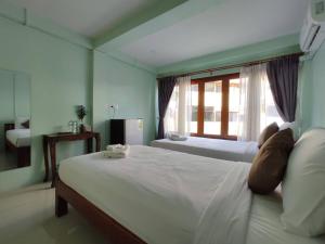 a bedroom with a large white bed with a window at Ban Mae Boonthong in Lampang