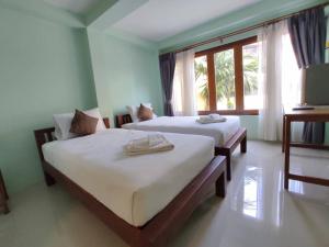 1 dormitorio con 2 camas y ventana en Ban Mae Boonthong, en Lampang