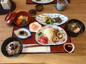 ヨーコのお宿 わくわく في توياما: صينية مع أطباق من الطعام على طاولة