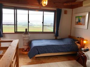 um quarto com uma cama e uma grande janela em ヨーコのお宿 わくわく em Toyama