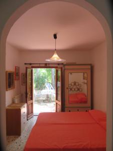 sypialnia z czerwonym łóżkiem i lustrem w obiekcie I GECHI - MARINA DI CAMPO w mieście Marina di Campo