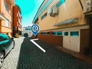 Darni Central Apartments - Bazaar Location With Free Parking في أوخريد: موقف للسيارة مع وجود لافتة موقف بجوار مبنى
