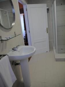 Baño blanco con lavabo y espejo en Hotel Rural Isasi en Gordexola