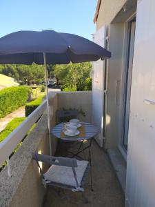 a table and chair under an umbrella on a balcony at Logement 88 2-4 Personnes 500 m plage classé 2 étoiles in Dolus d'Oléron