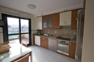 kuchnia z drewnianymi szafkami i dużym oknem w obiekcie Atico centro Oviedo 3hab+garaje+terraza+wifi w mieście Oviedo