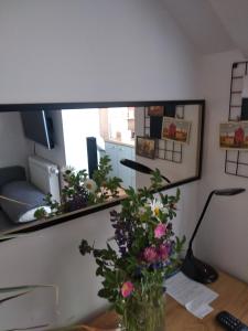 a vase of flowers on a desk with a mirror at Copernicus 11 in Olsztyn