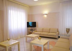 a living room with a couch and tables and a tv at Hotel Fernanda in Cesenatico