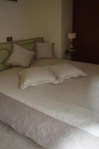ヴィアレッジョにあるCasa Ilianaのベッド(白いシーツ、枕付)
