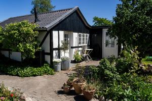 uma pequena casa a preto e branco com plantas à frente em Svenskebakken Bed & Breakfast em Roskilde