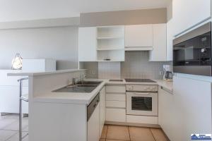 a white kitchen with a sink and a microwave at Golvenzang 0401 in Koksijde