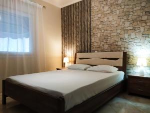a bedroom with a large bed and a stone wall at Iro Apartment in Nea Peramos