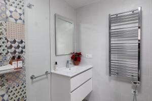 a white bathroom with a sink and a mirror at Anayet - Plaza del Reloj en FORMIGAL - Reformado in Formigal