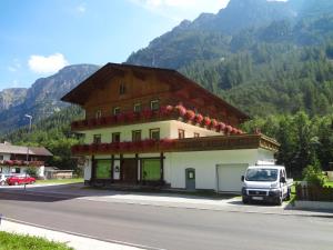 um edifício na berma de uma estrada com uma carrinha estacionada em frente em Gasthof Alpenrose und Pension Nina em Gschnitz
