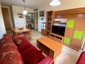 un salon avec un canapé rouge et une télévision dans l'établissement APARTAMENTO 2ª LINEA DE PLAYA, à Roquetas de Mar