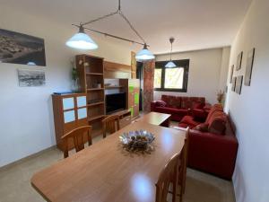 APARTAMENTO 2ª LINEA DE PLAYA في روكويتاس دي مار: غرفة معيشة مع طاولة وأريكة حمراء